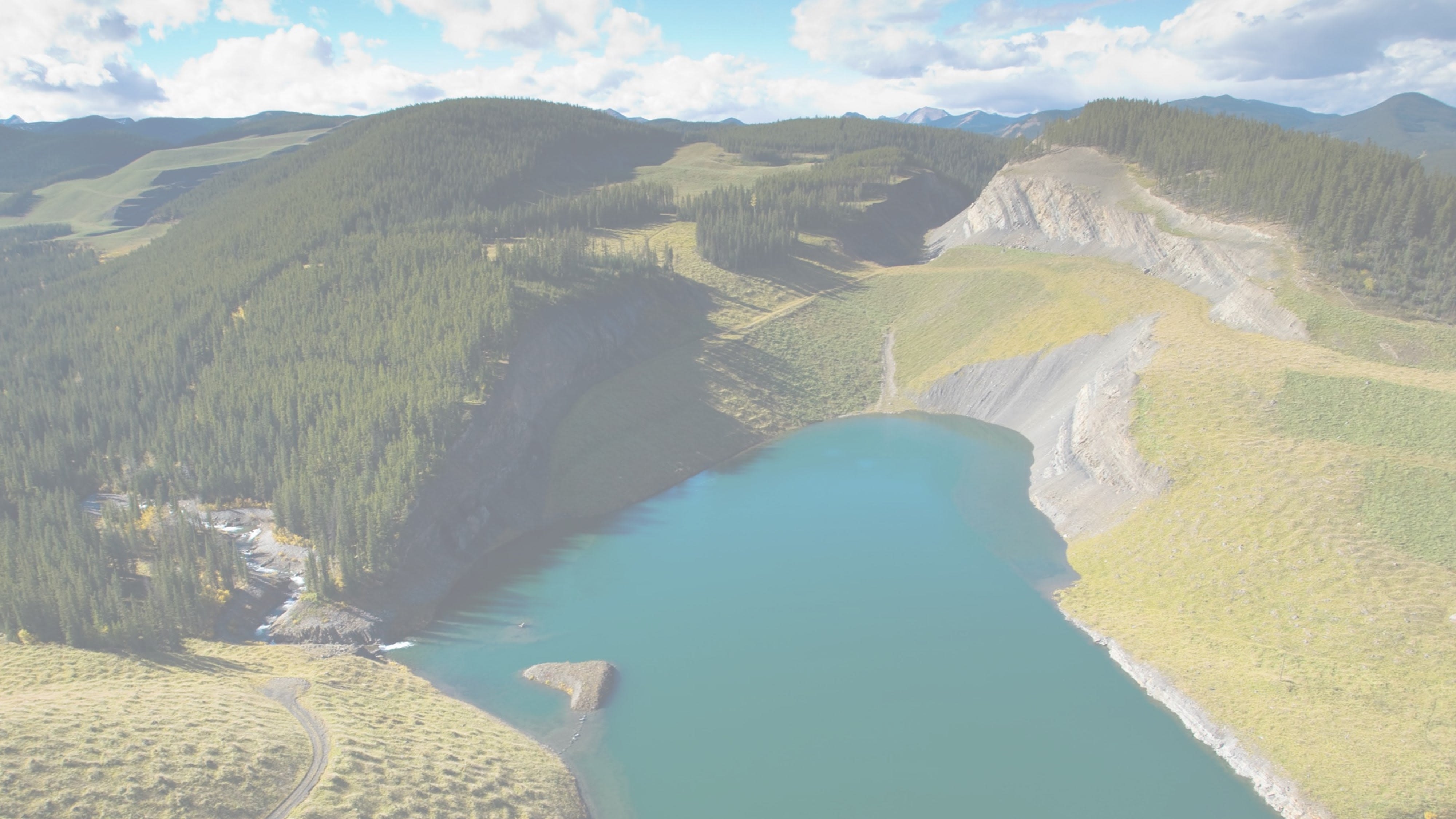 Sphinx lake, Canada. Blue lake in a pit, surrounded by green slopes. White fade out background.