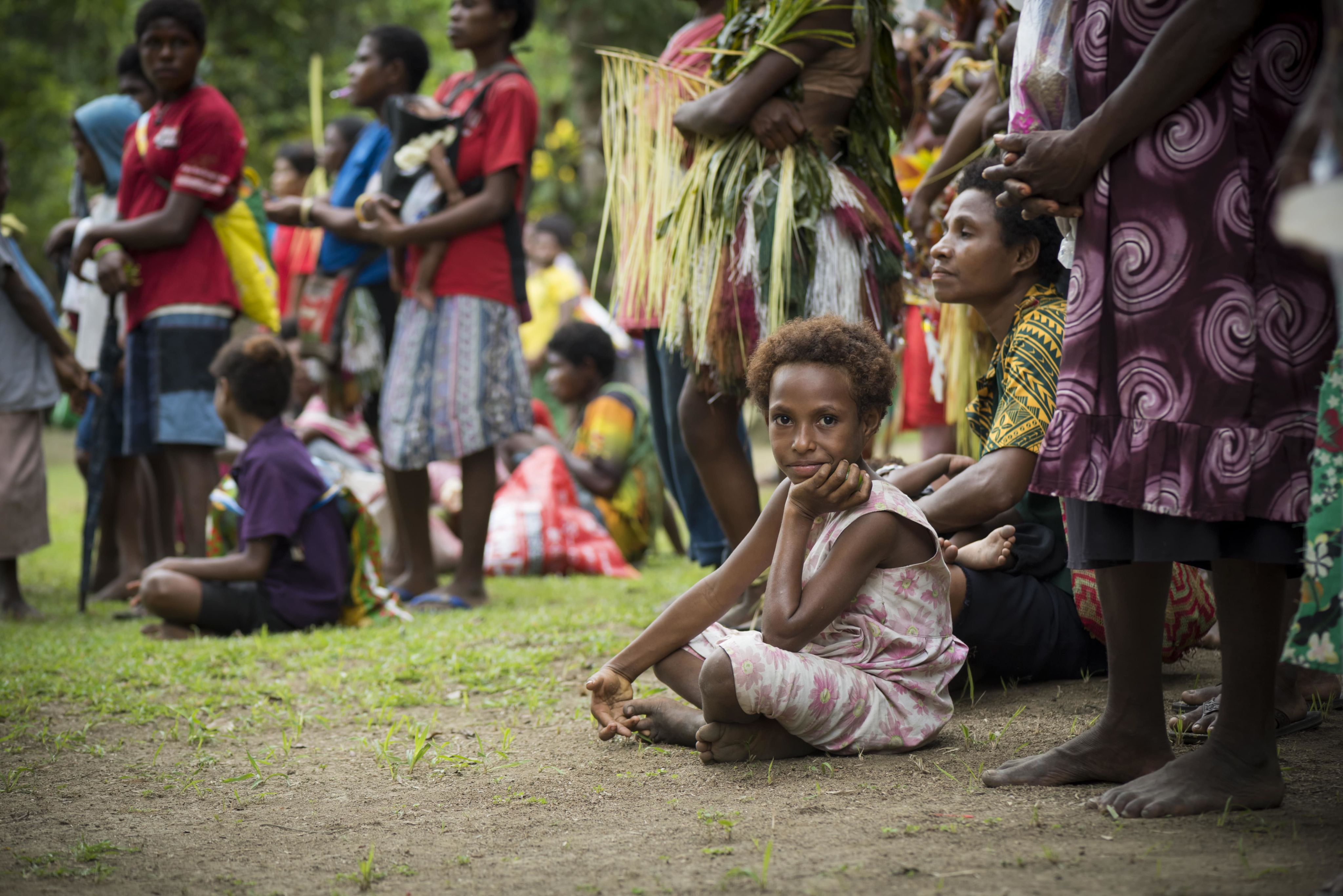 A young girl sits on the ground during a celebration in Tambapmining, a village on the lower Ramu River in Madang Province, Papua New Guinea (2017)