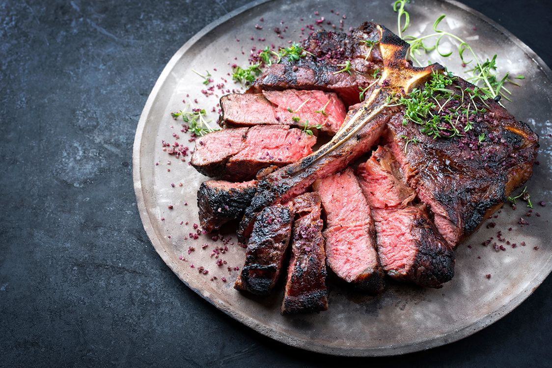 Plate of wagyu beer cut into pink-coloured slices around the central piece of bone