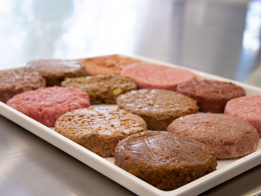 white-coloured tray of meat and plant-based patties in a circular shape