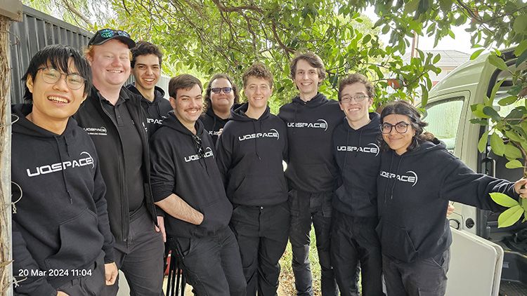 8 people standing in a group, all wearing 'UQ Space' hoodies