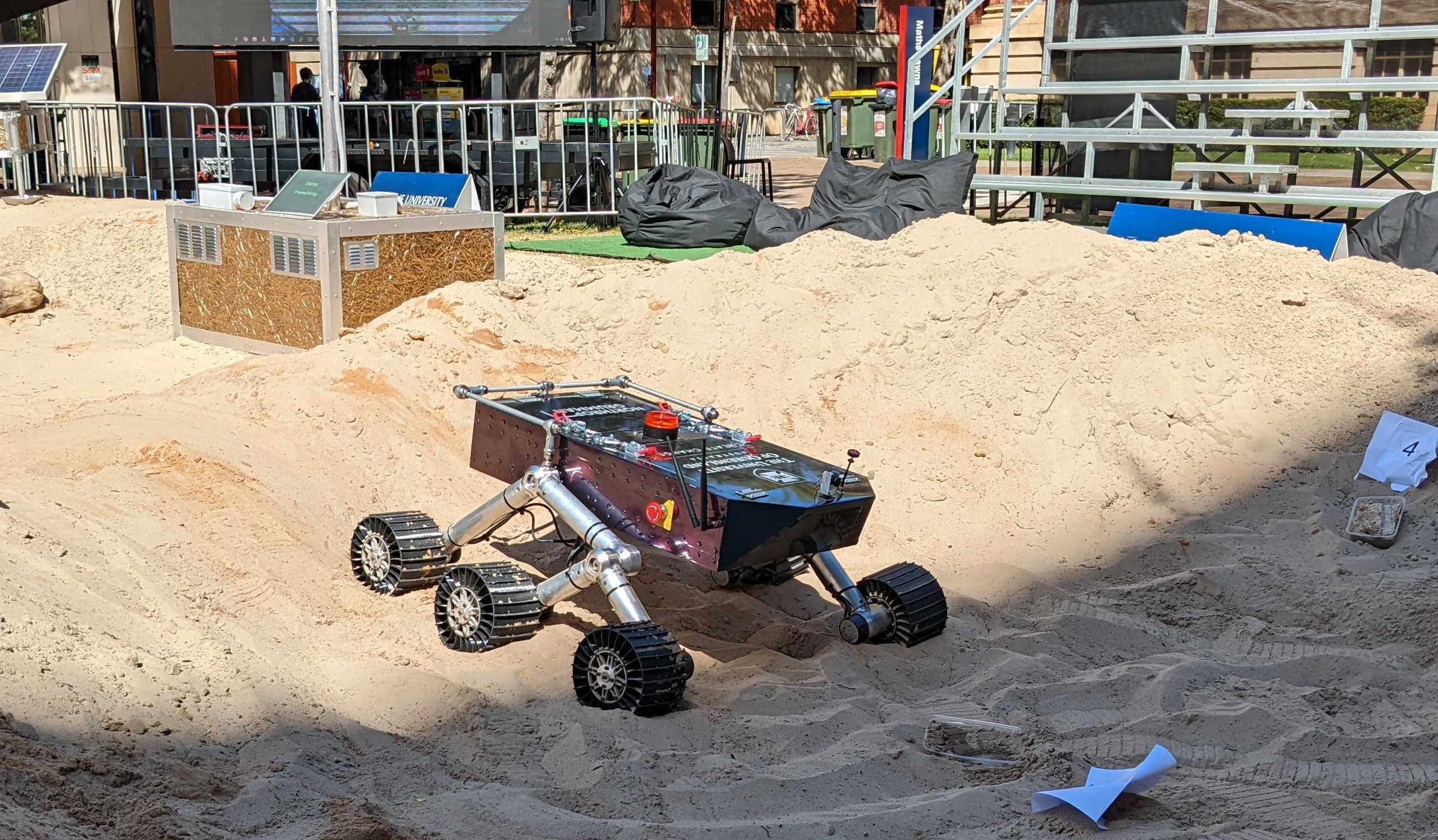 A six-wheeled vehicle driving through sand