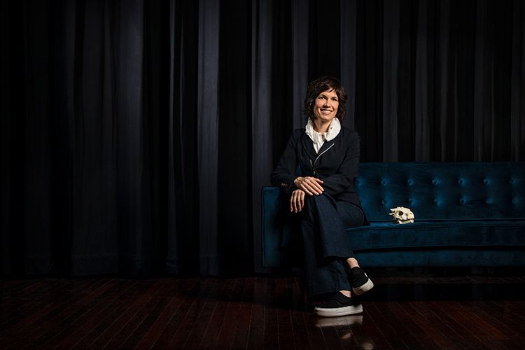 Image of Deborah Riley sitting on a couch with a dragon skull beside her.