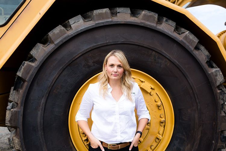 Image of Sally McPherson standing in front of truck wheel.