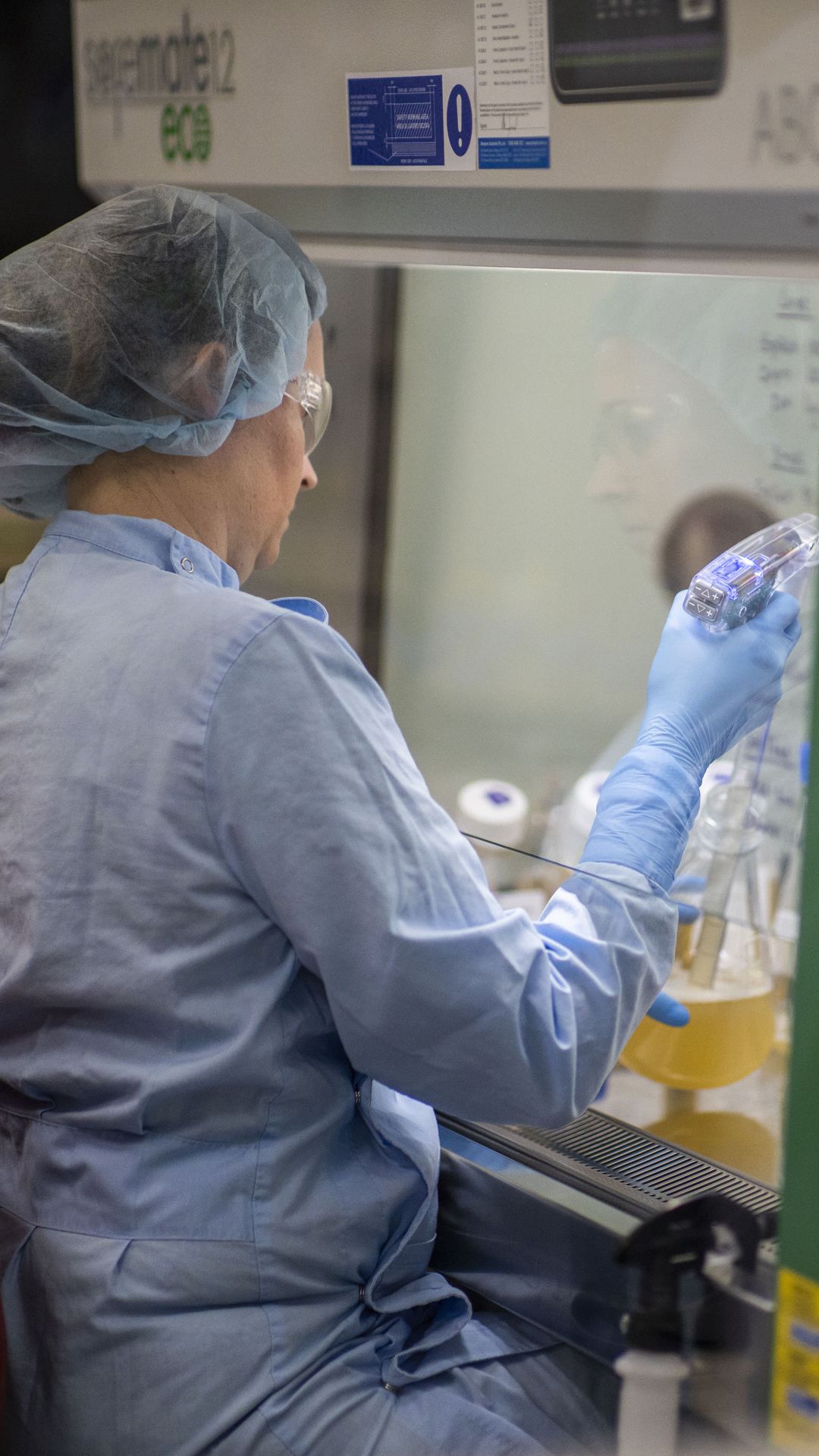 Image of a UQ COVID-19 vaccine researcher with a pipette in protective clothing