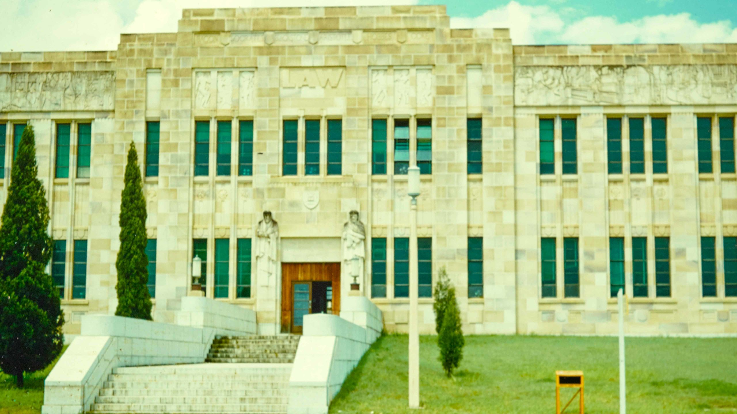 The strong sandstone facade of the Forgan Smith building at UQ, which houses the T.C. Beirne School of Law. Two sandstone carvings of men flank either side of the door.
