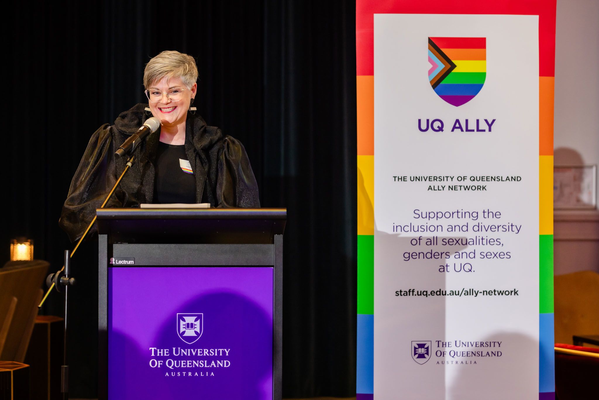 Professor Heather Zwicker, Executive Champion of UQ’s Ally Network, presents at a function in front of a UQ Ally sign.