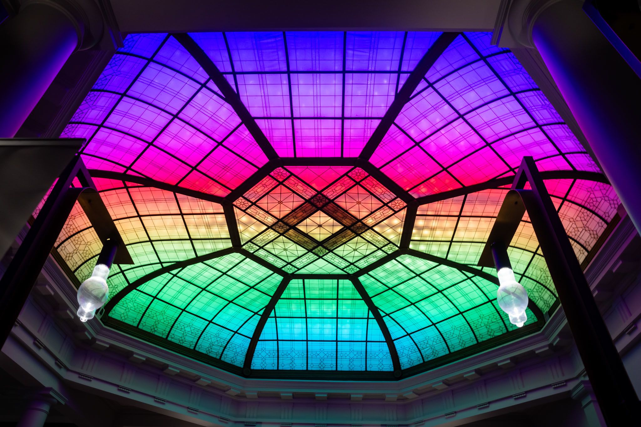 The ceiling of Brisbane City Hall's Main Auditorium is lit up in a rainbow.