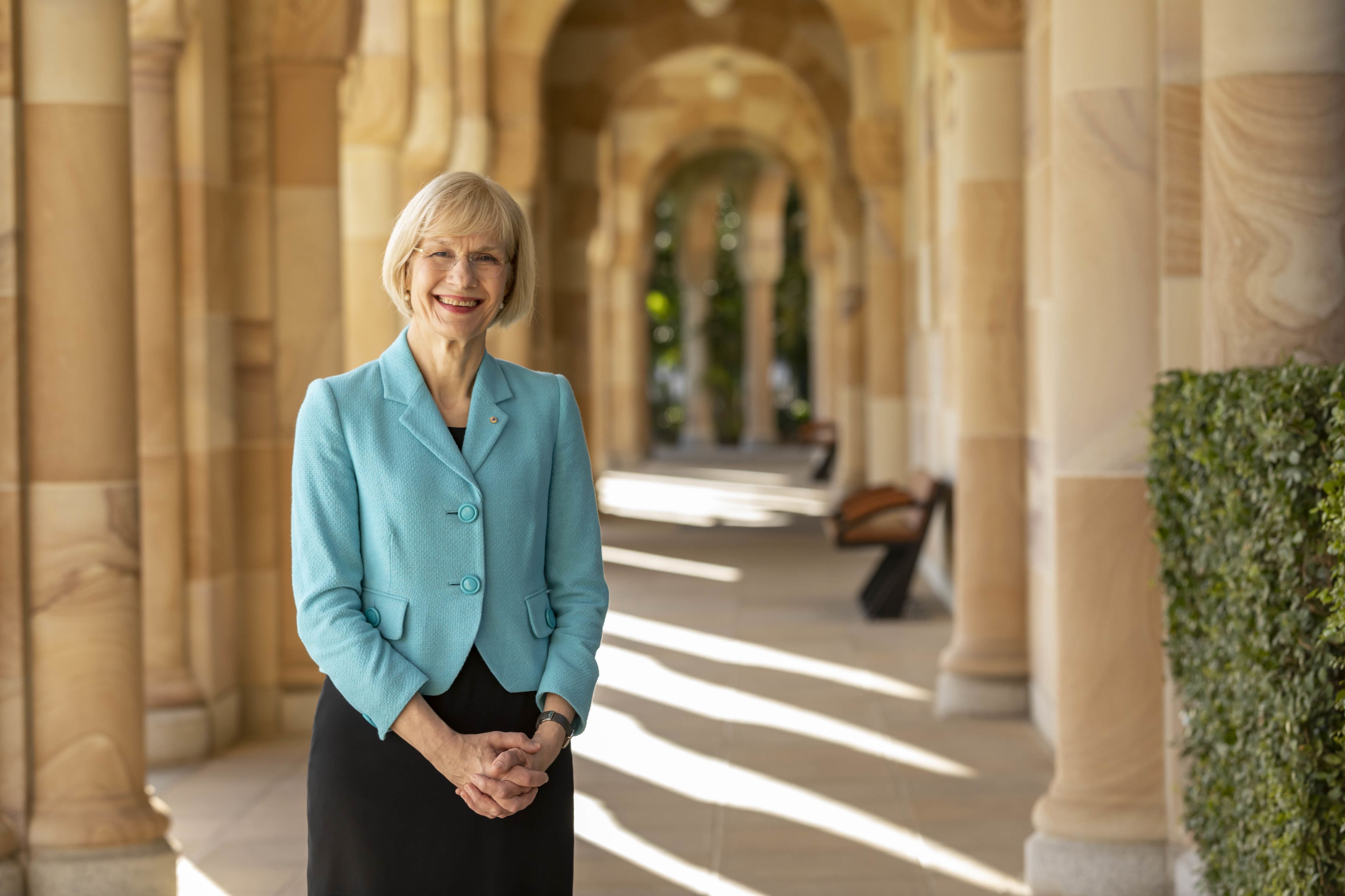 An image of Professor Deborah Terry AC among the sandstone archways of the Great Court