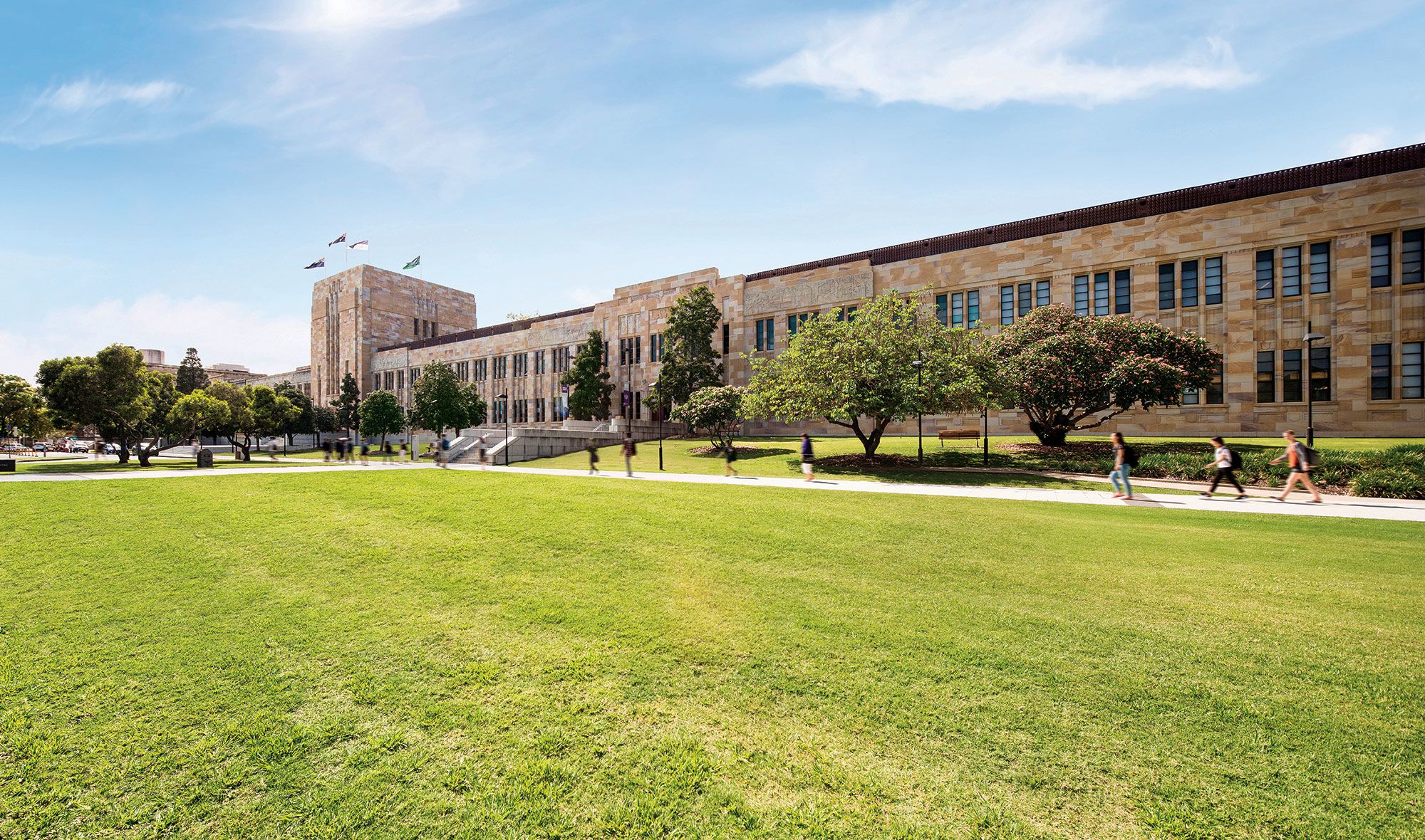 UQ's Forgan Smith building on a sunny day with students walking next to it.