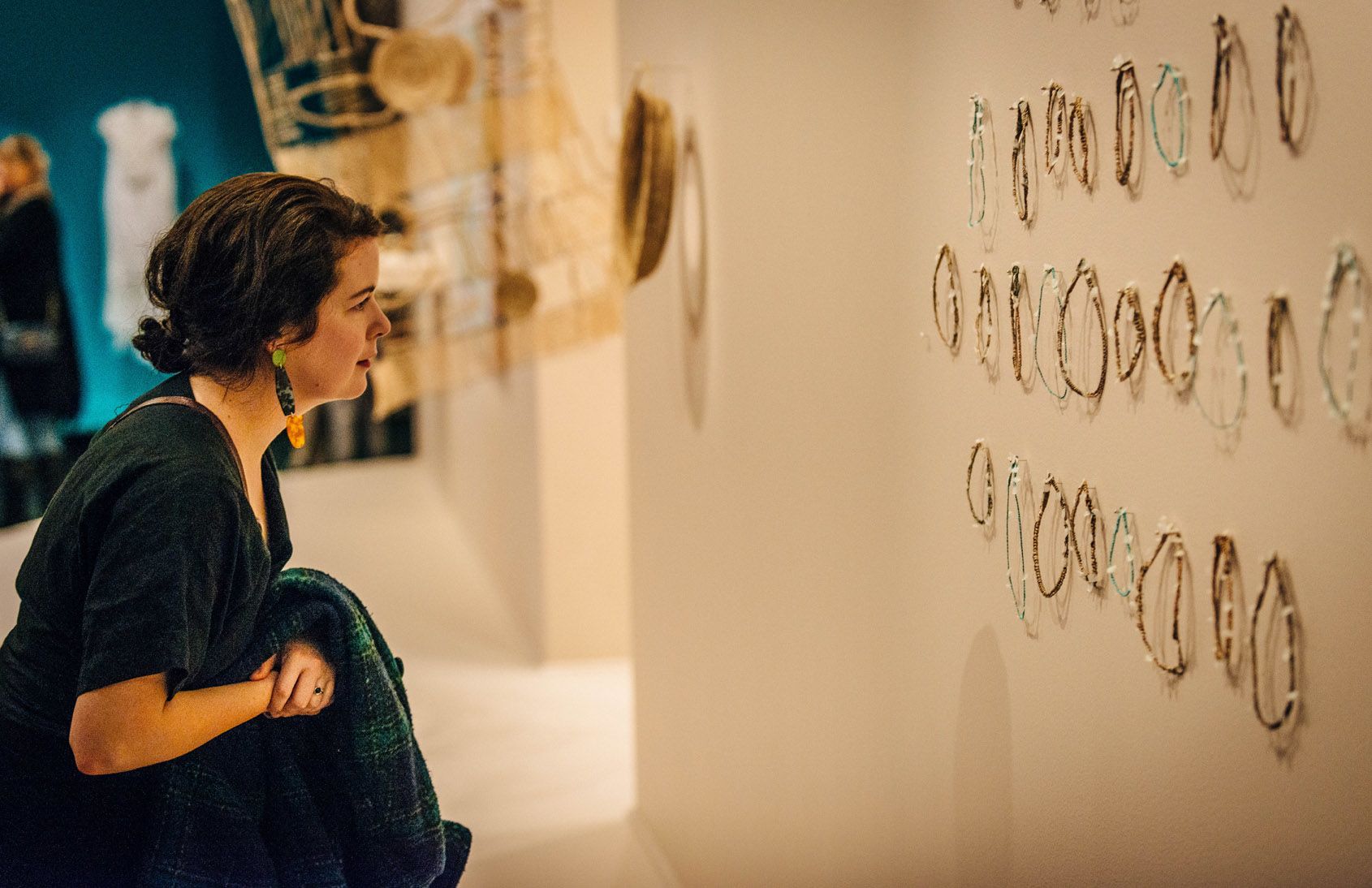 A woman inspects Elisa Carmichael's artwork Rain from the heart at the opening of the Weaving the way exhibition at UQ Art Museum.