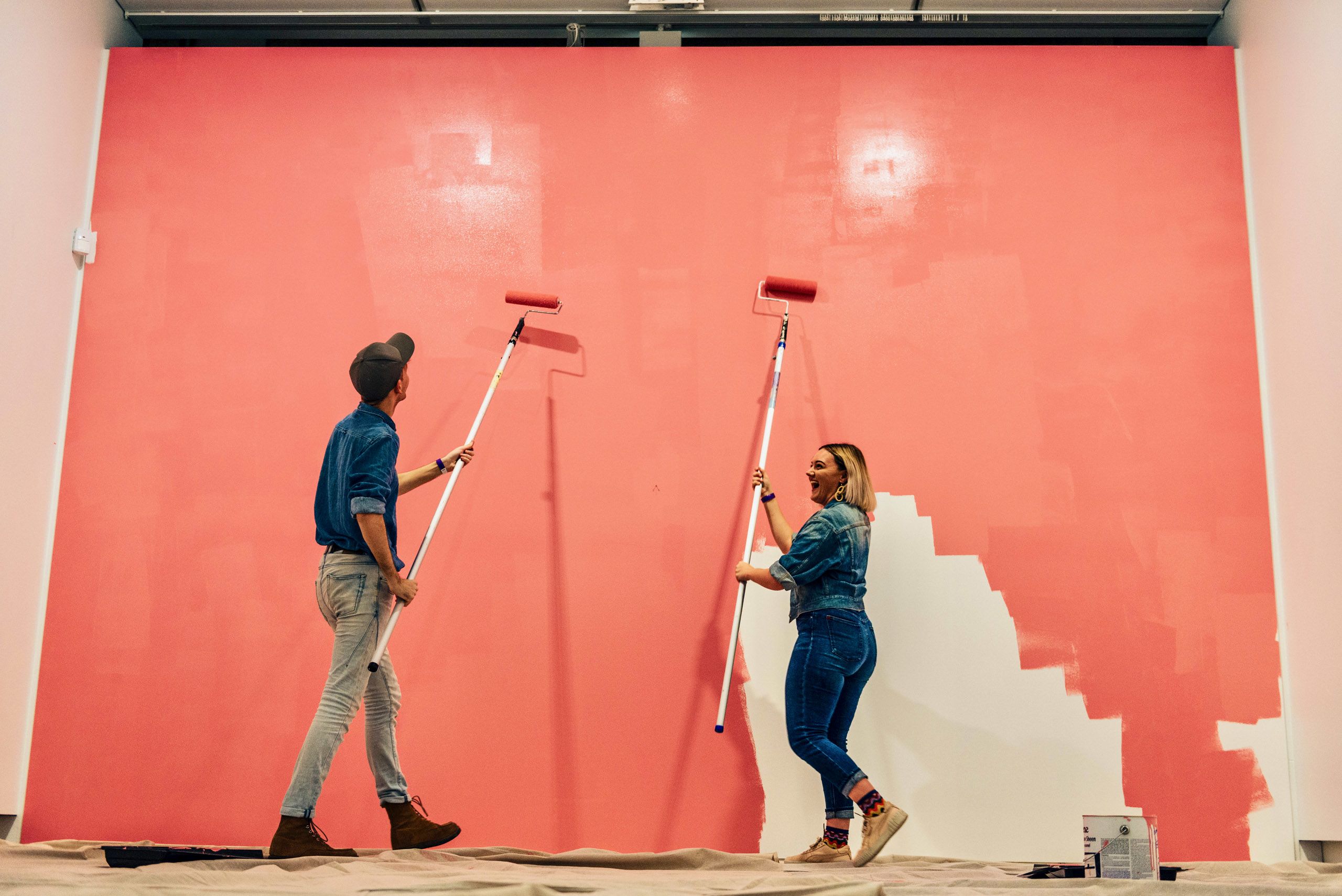 Two students painting the wall bright pink for the Baldessari Wall Painting project.