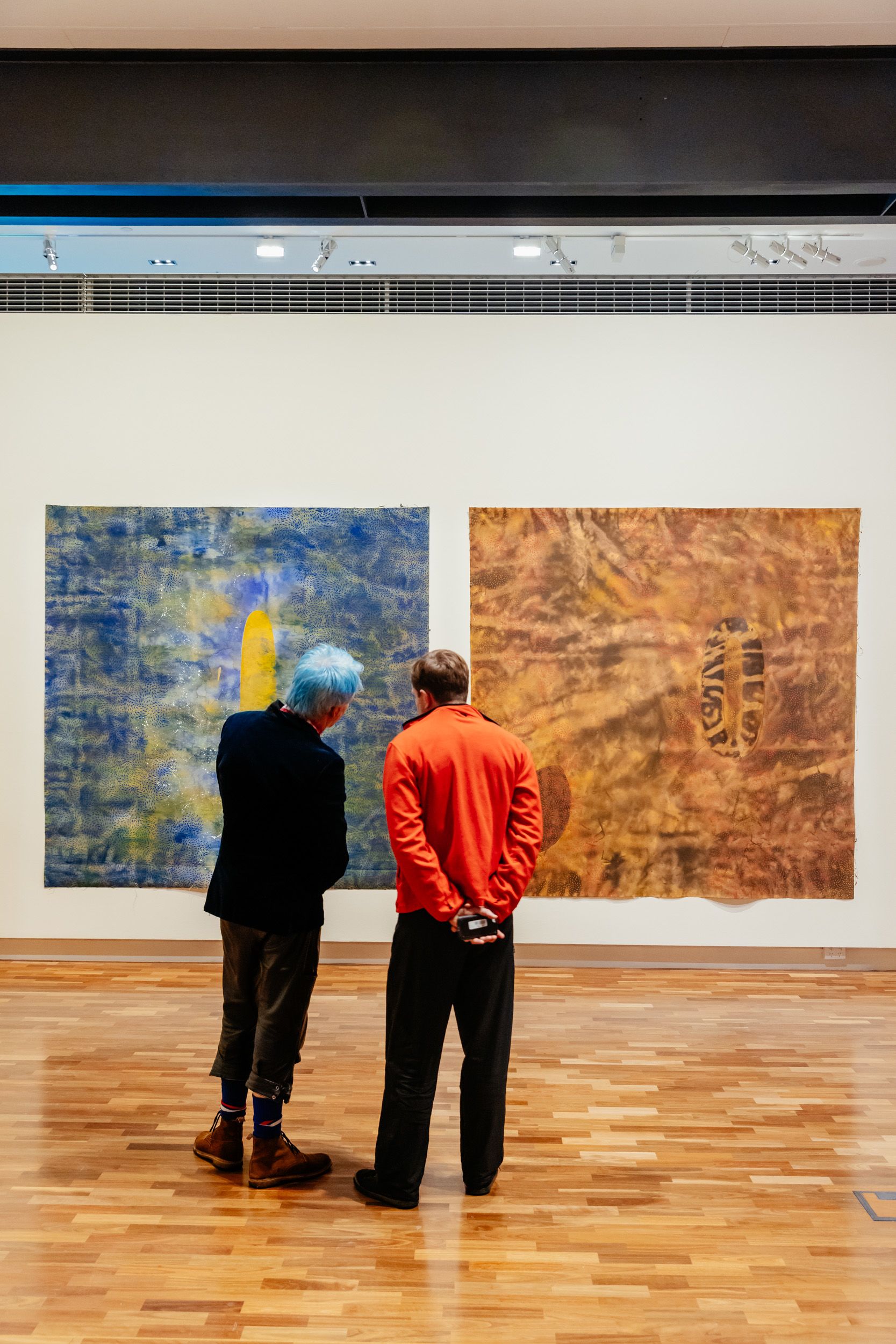 Two people standing and looking at art in a gallery