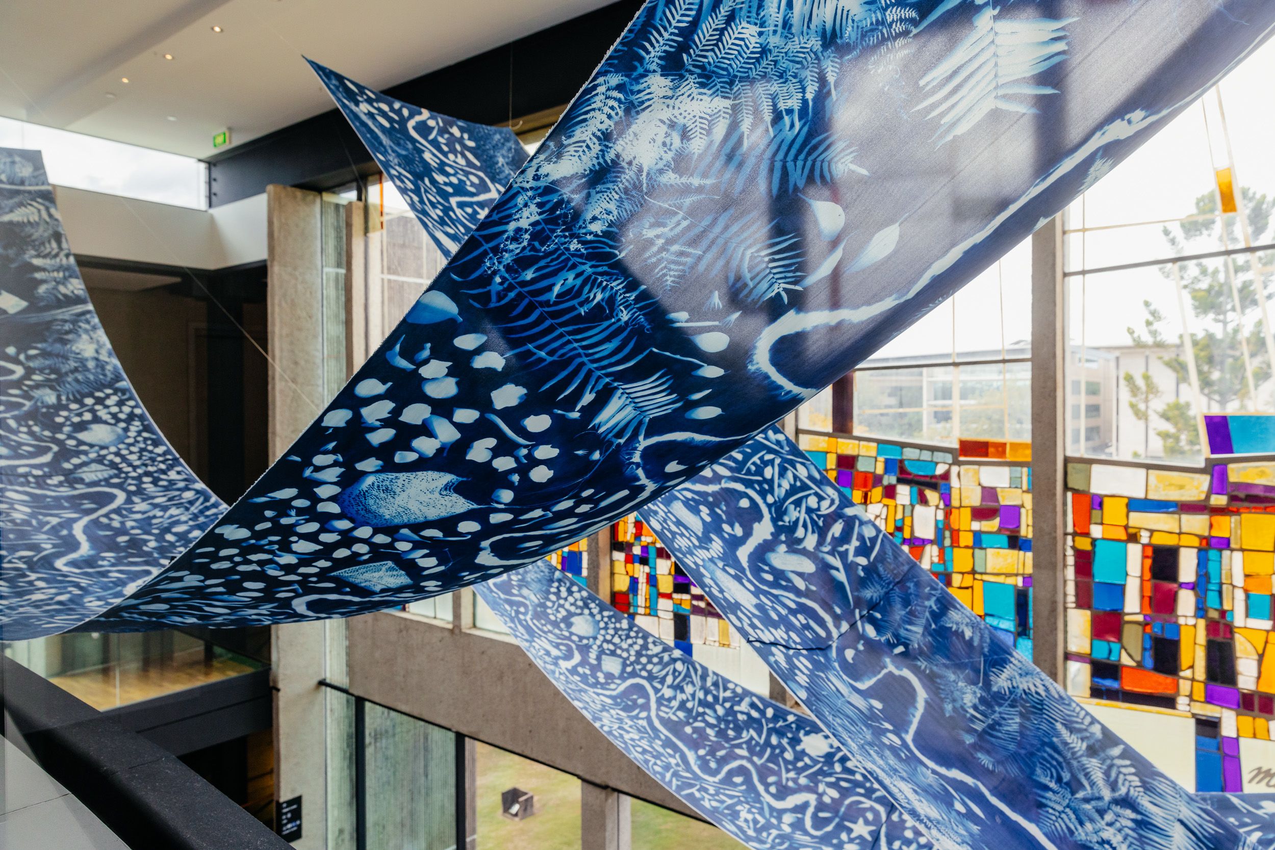 Two blue silk fabric panels draped in curved lines from the ceiling in front of stained glass windows