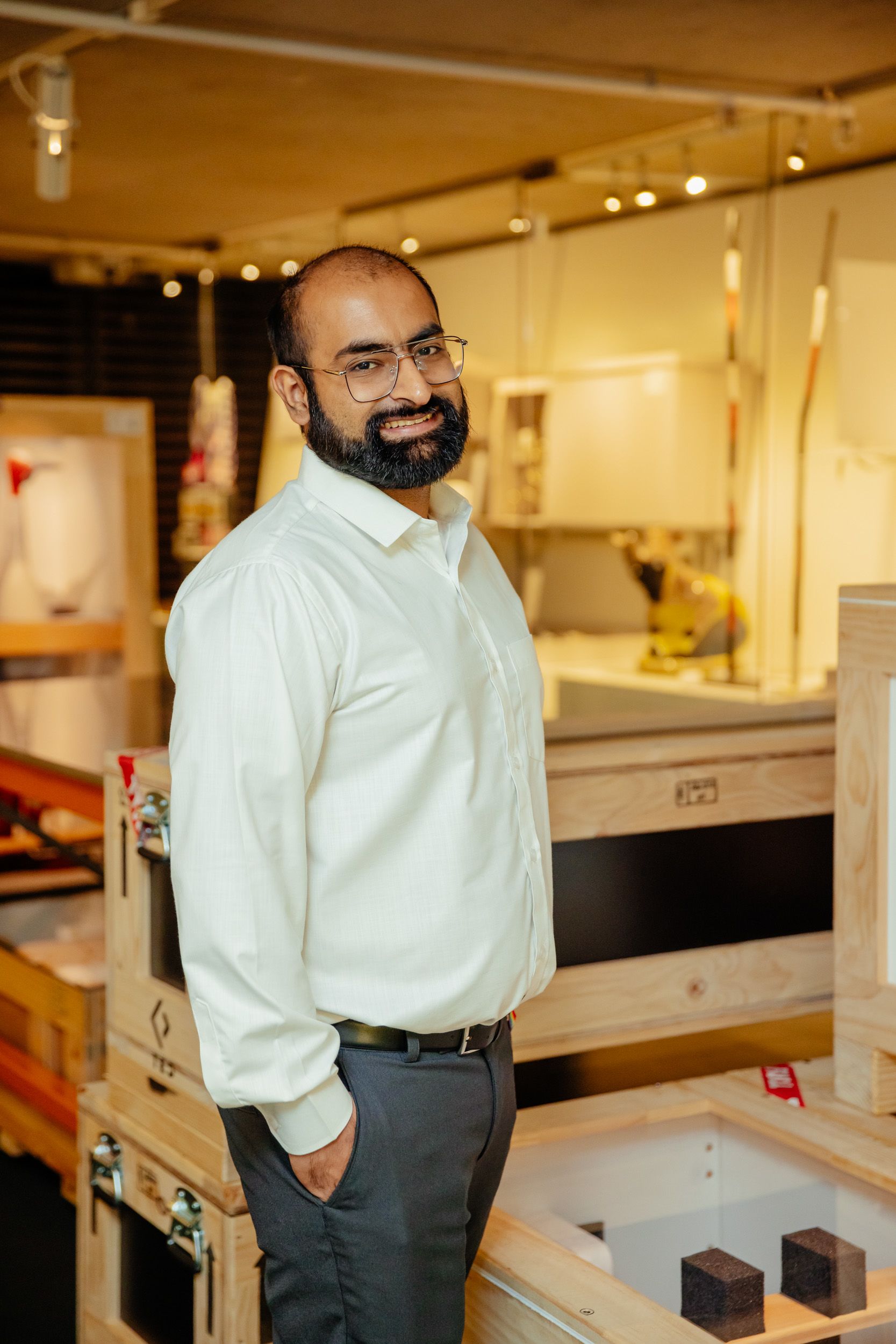 A person standing in front of wooden storage crates and smiling at the viewer.