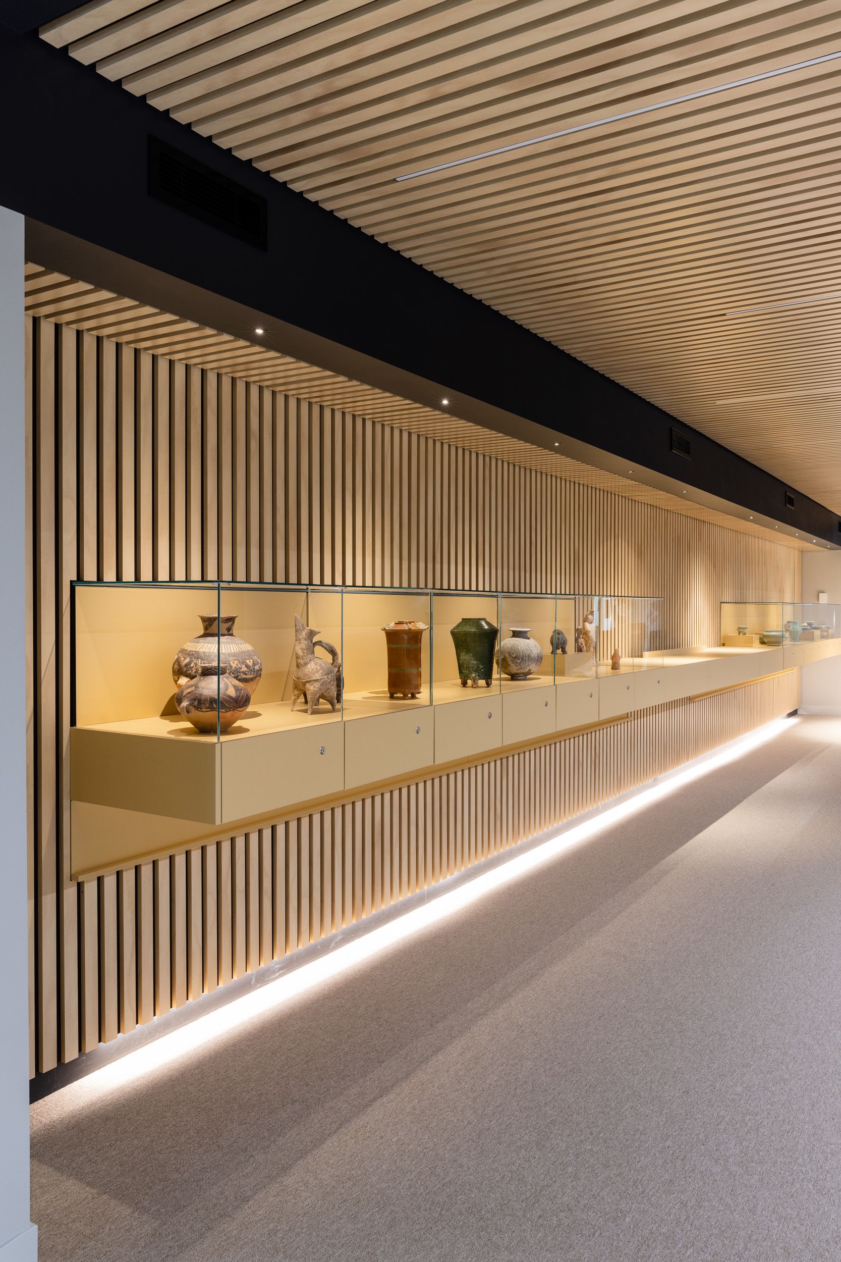 A collection of vases and clay sculptures in a long glass display case