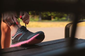 tying laces on pink and black running shoes
