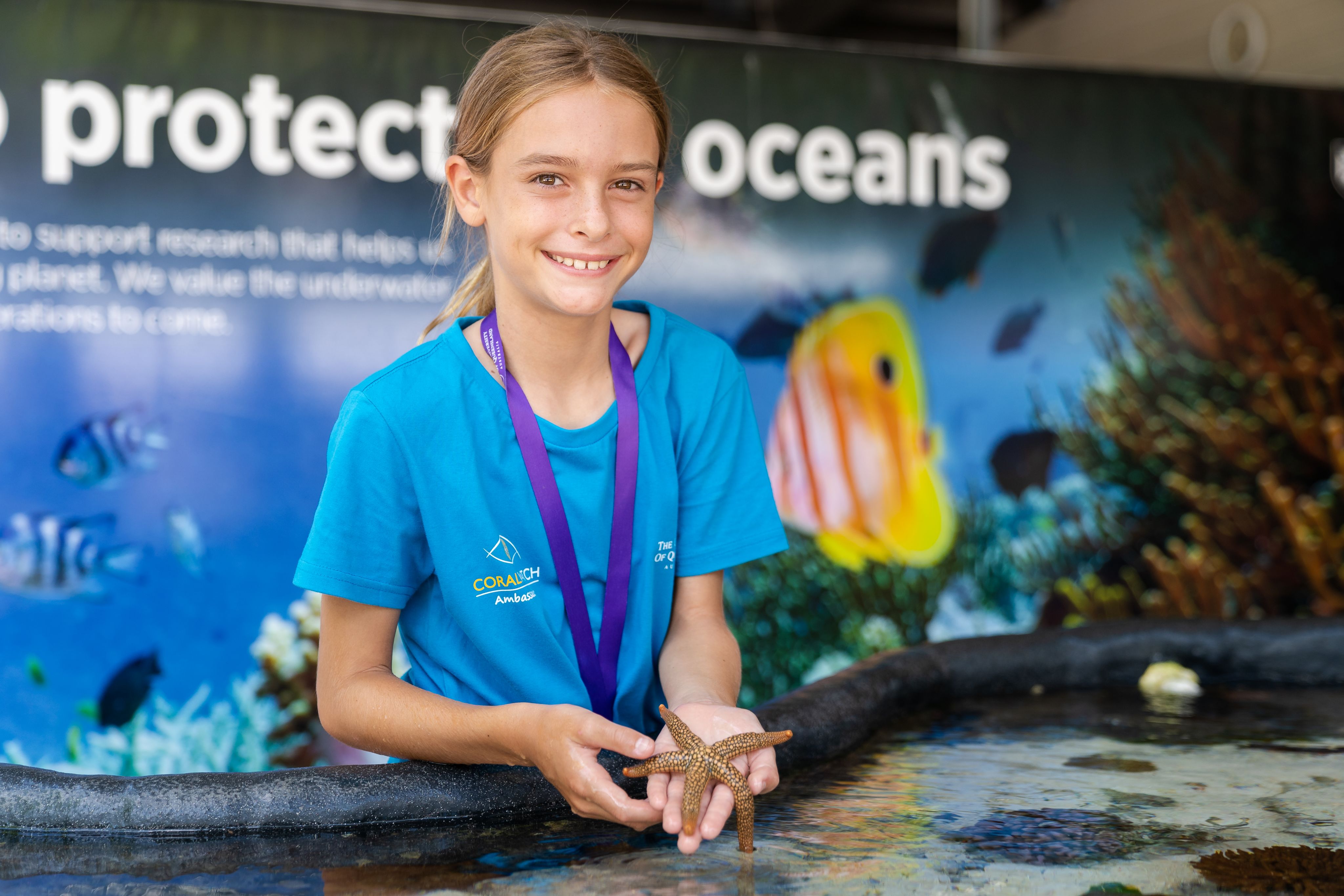 A young boy in a blue shirt showing a starfish from a touch tank