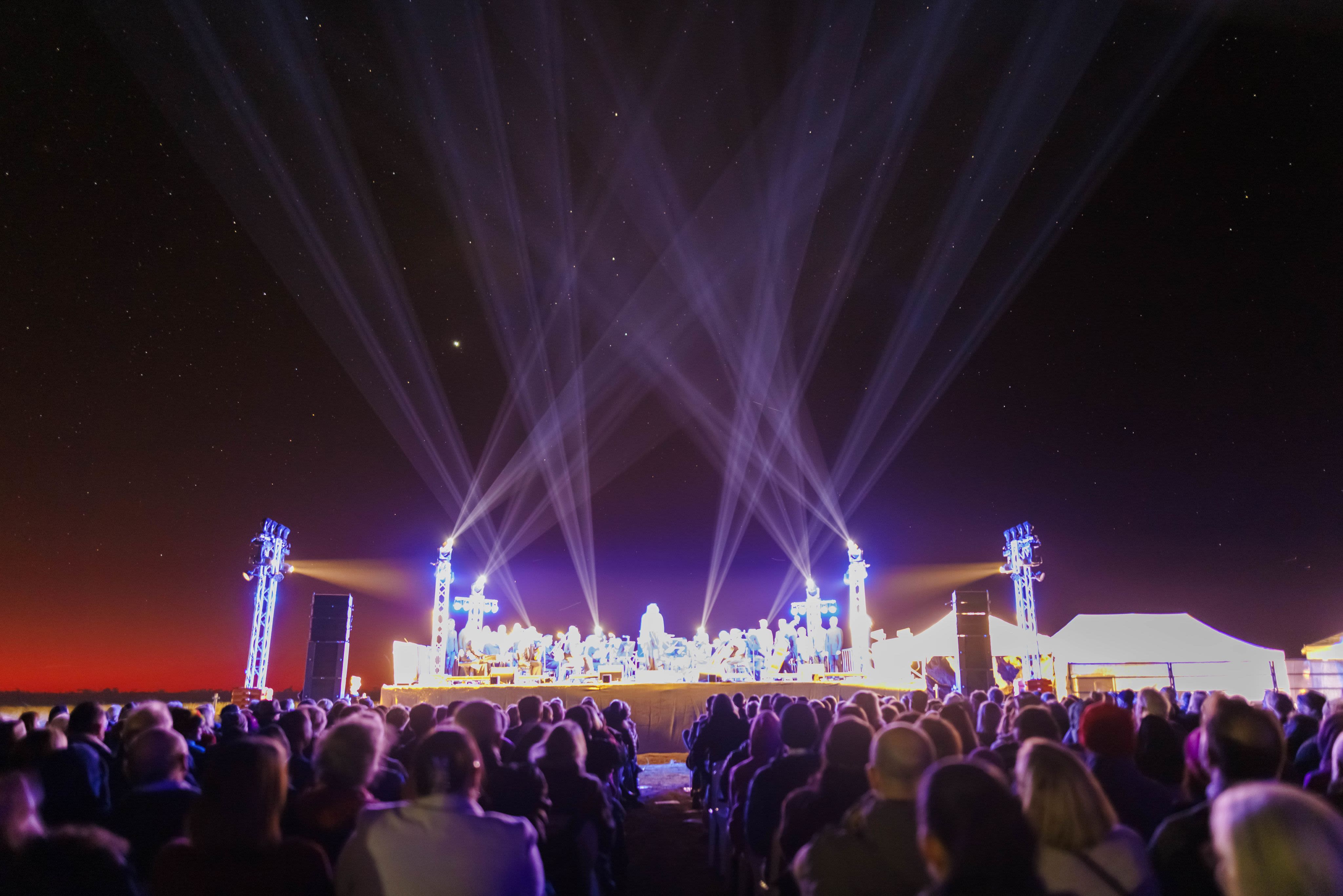 A bright stage of performers under a purple starry nighty sky
