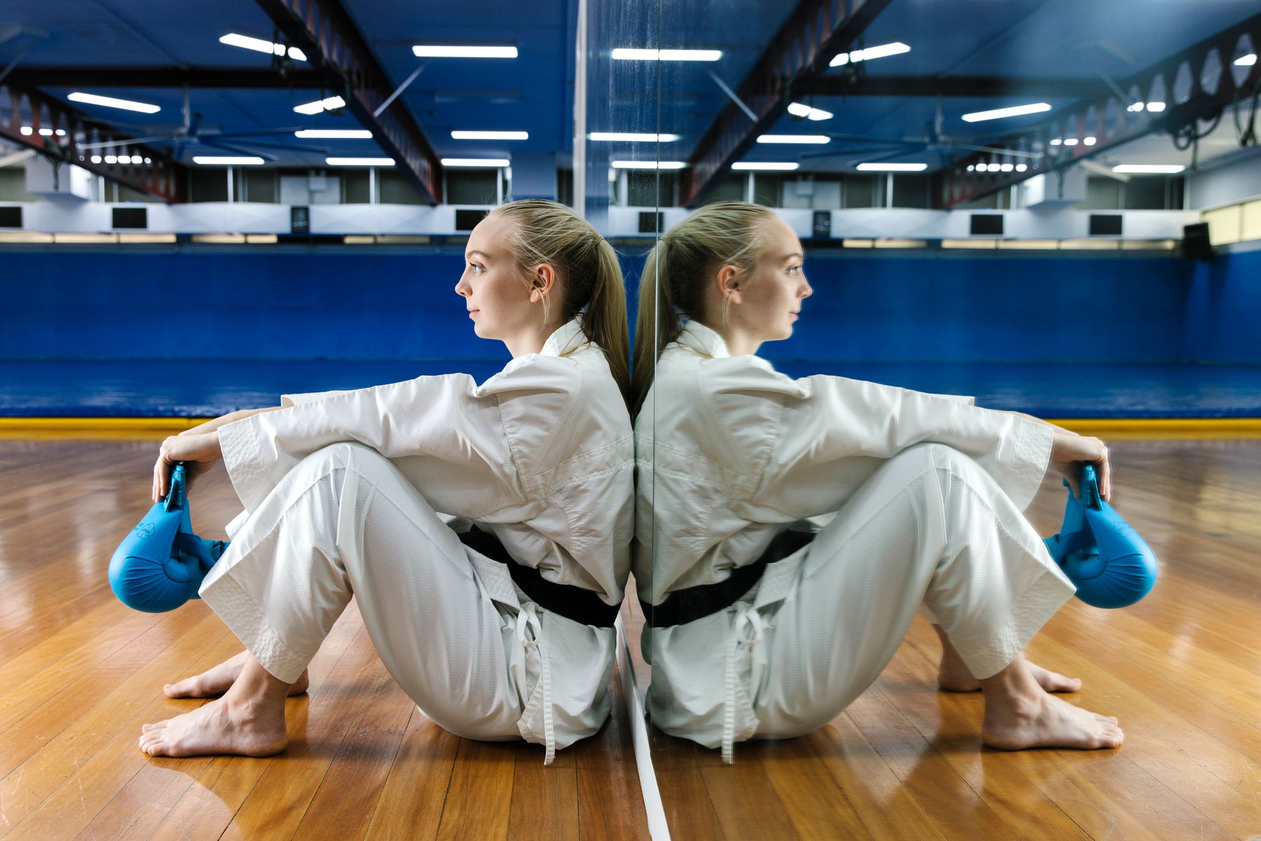 This is an image of UQ student and karate champion Alannah Schramm sitting in the martial arts gym at UQ.