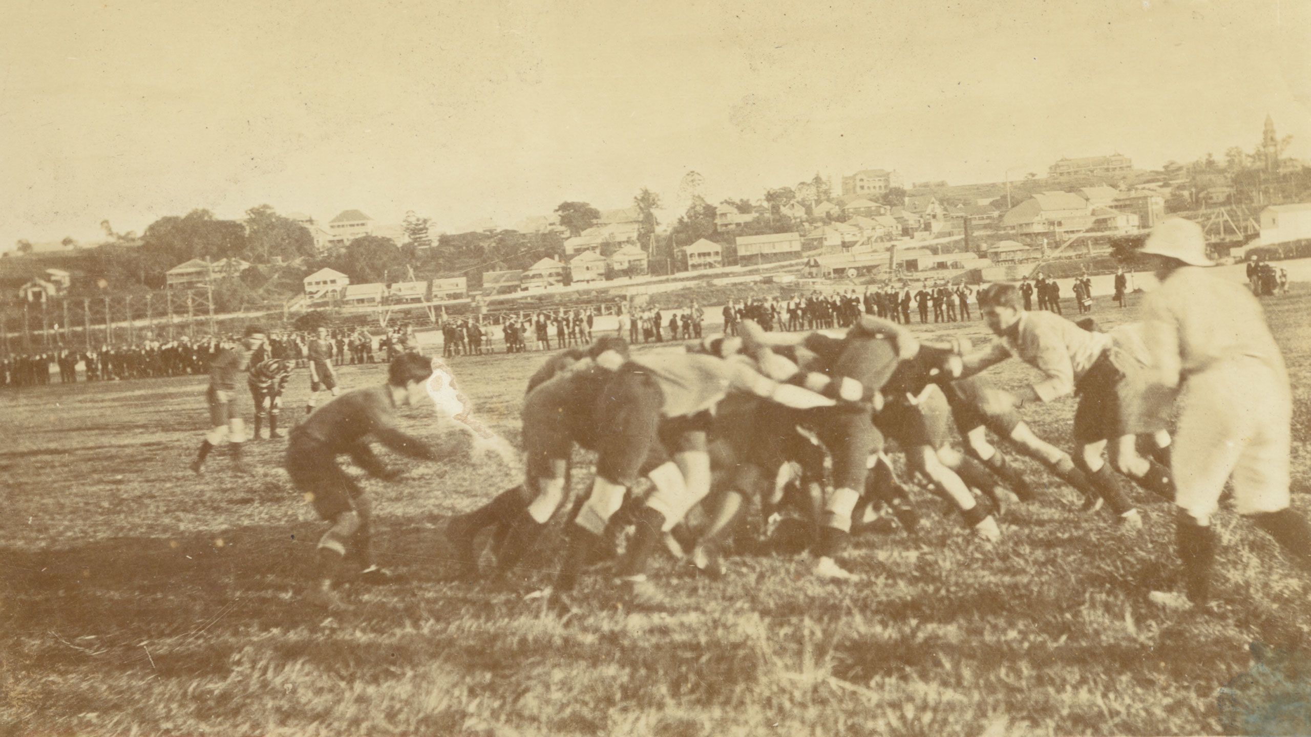 An action image of The University Football Club versus the Queensland Combined Schools in 1918.