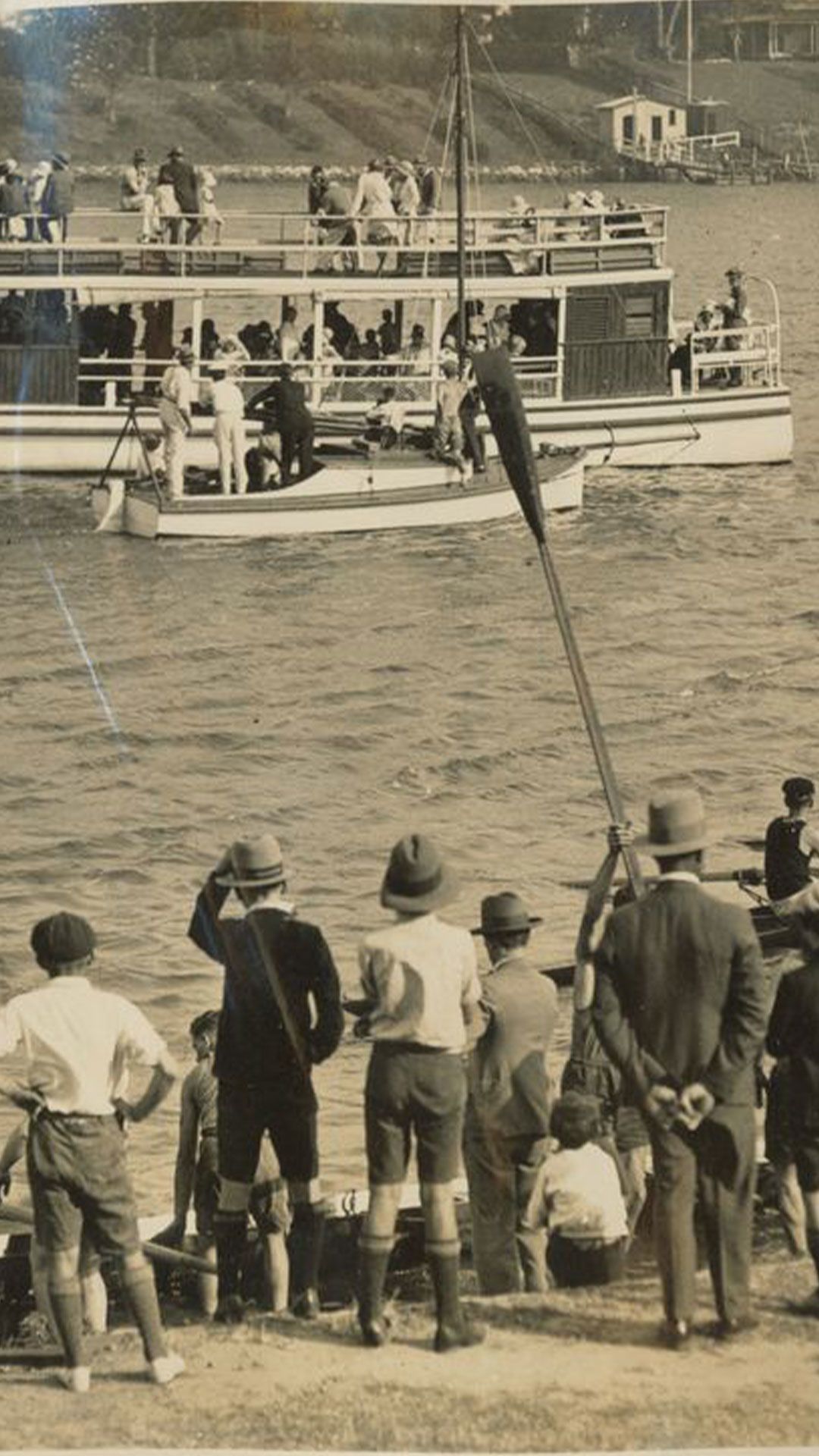 An image showing the crowd gathering on the river bank and on the river to watch the Toowong Rowing Club Regatta in 1930.