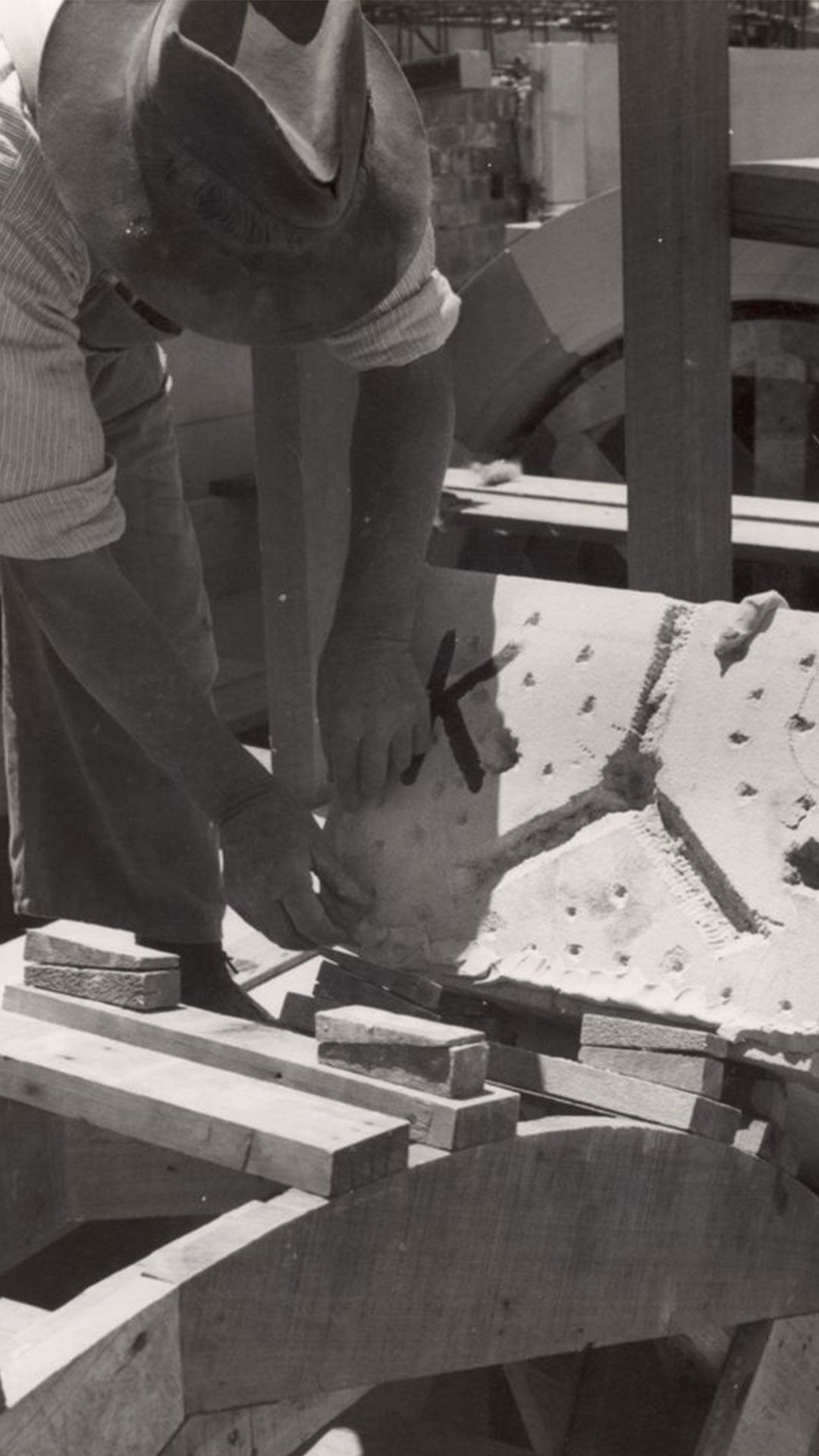 An image of workers maneuvering a piece of carved sandstone into position on the Forgan Smith building in 1939.