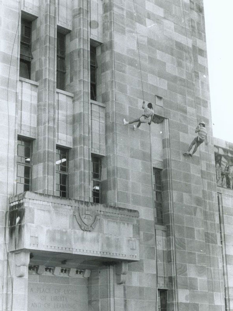 An image of two members of the UQ Bush Walking Club abseiling down the side of the Forgan Smith building in 1975.