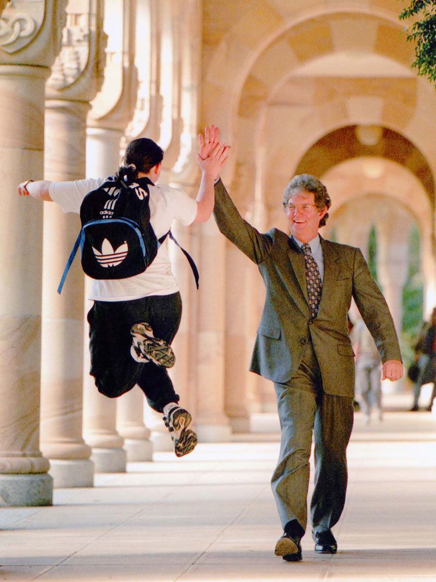 An image of UQ Vice-Chancellor and President Emeritus Professor John Hay AC high fives a student Jane Cooper in 1998.