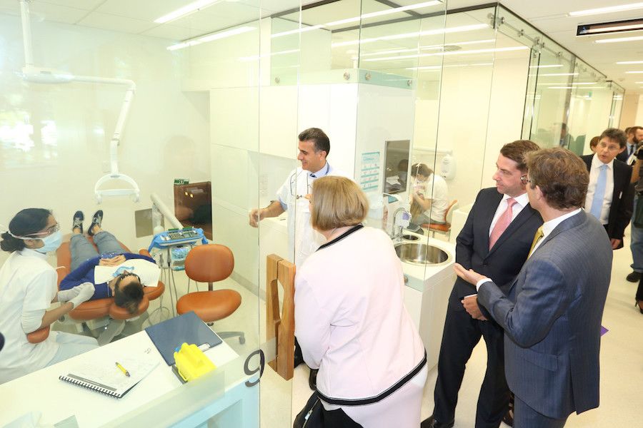 An image of a dentist assisting a patient while several others look on.
