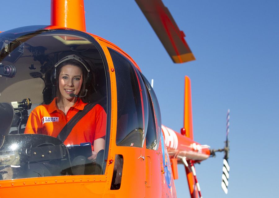 An image of a woman in an orange t-shirt sitting in an orangehelicopter.