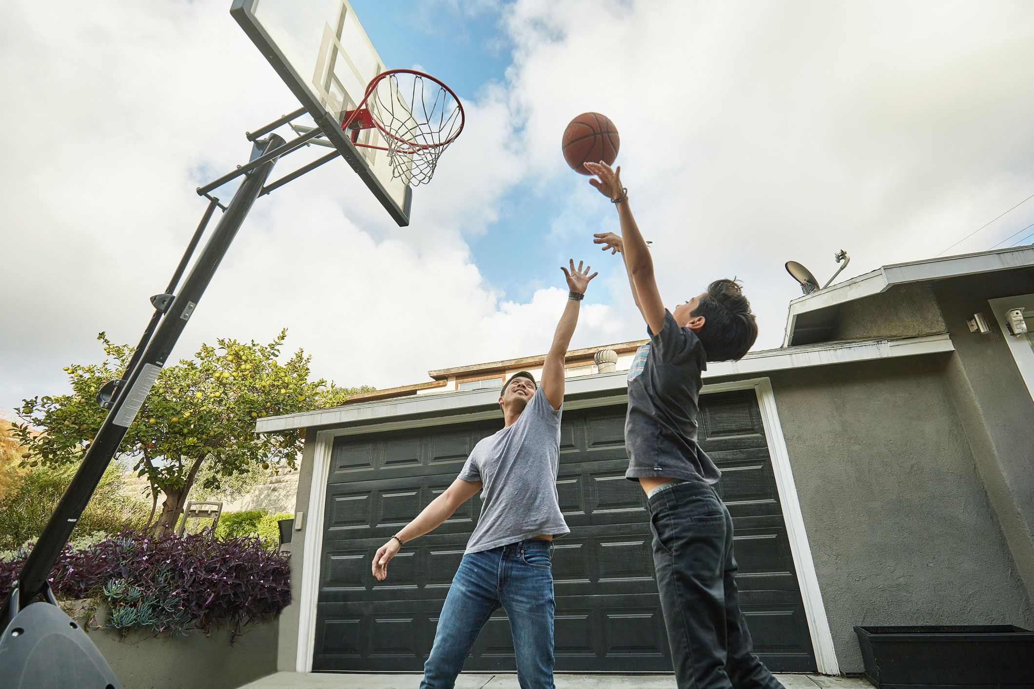 An image of a dad playing basketball with his son in the family yard.