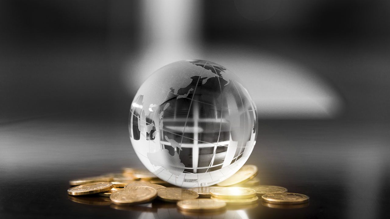 An image of a crystal globe on piles of coins.