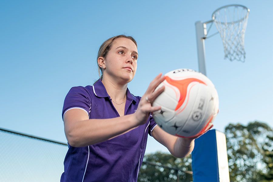An image of UQ Firebirds Scholarship recipient Brooke Warburton passing a netball.