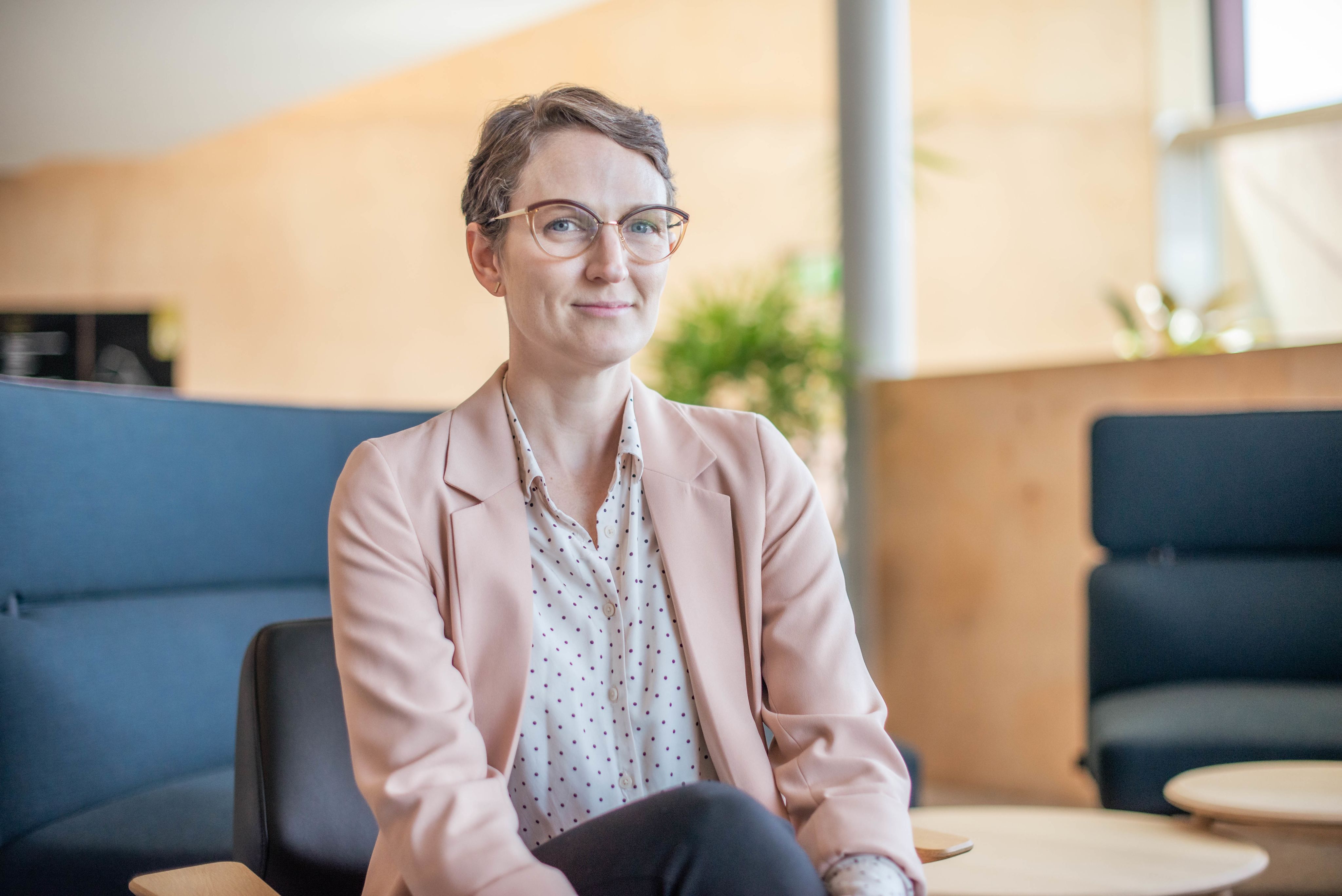 Dr Angie Knaggs sitting on a black chair in the foyer of the Sir Llew Edwards building