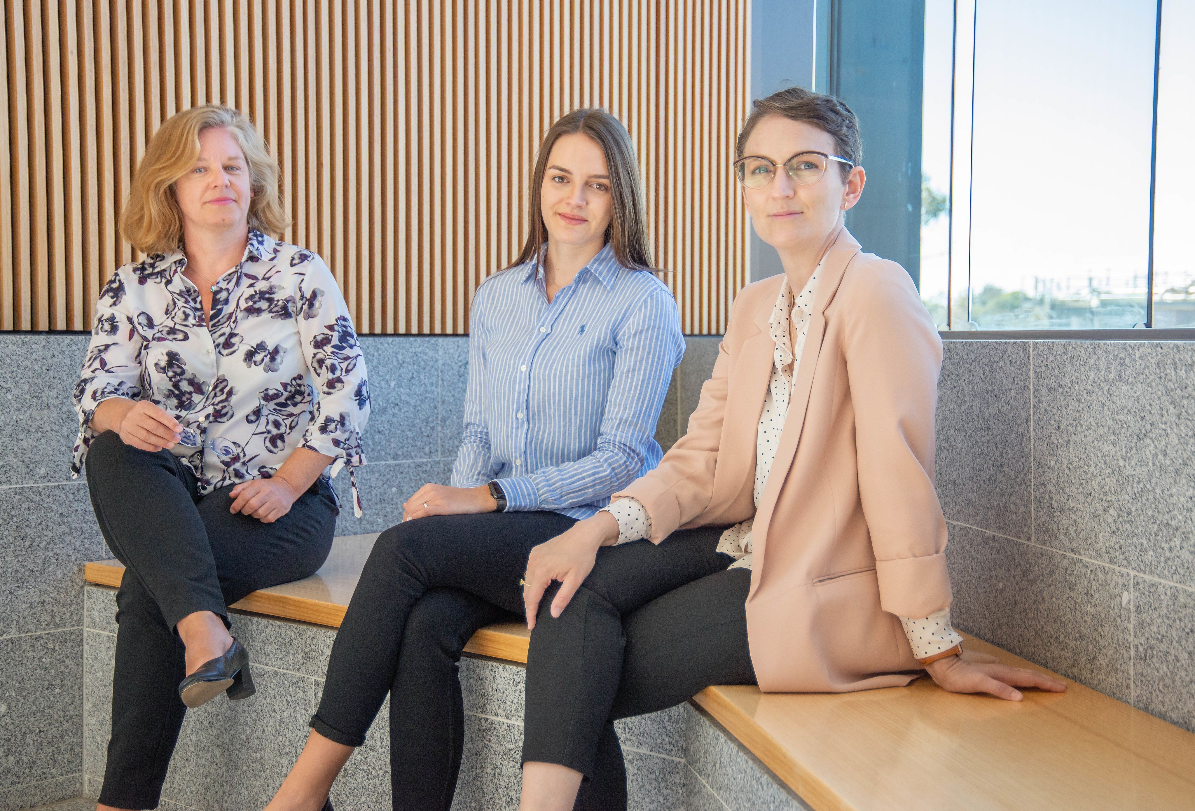 Dr Sabine Matook, Lara Harbers and Dr Angie Knaggs sitting in the foyer of the Sir Llew Edwards building together