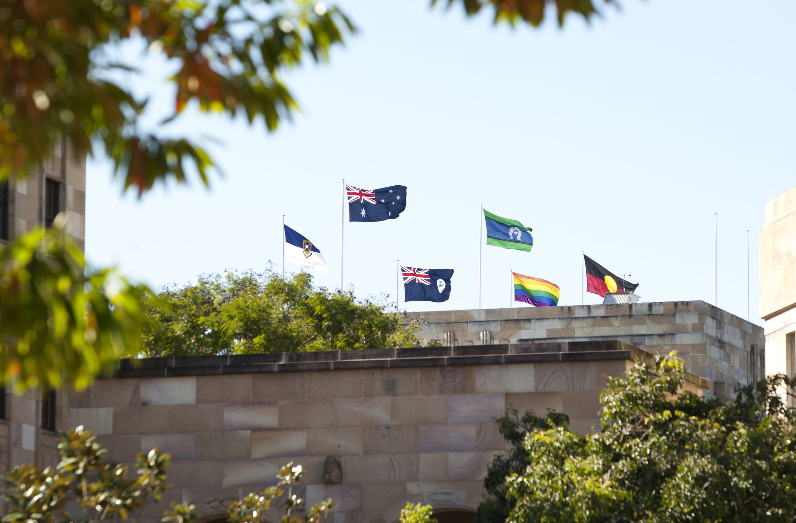 An image of the rainbow pride flag flying above the Forgan Smith tower at UQ.