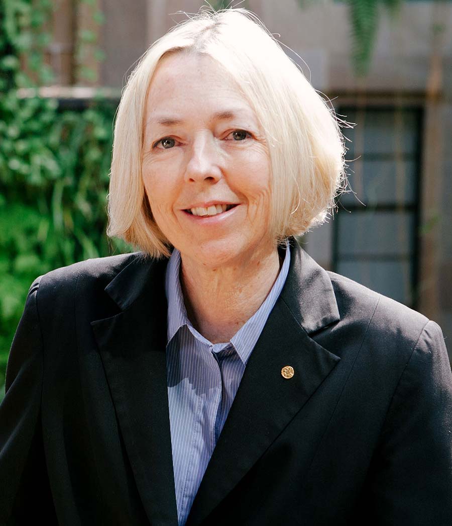 A headshot of a woman with short blond hair wearing a blazer and business shirt smiles into the camera.