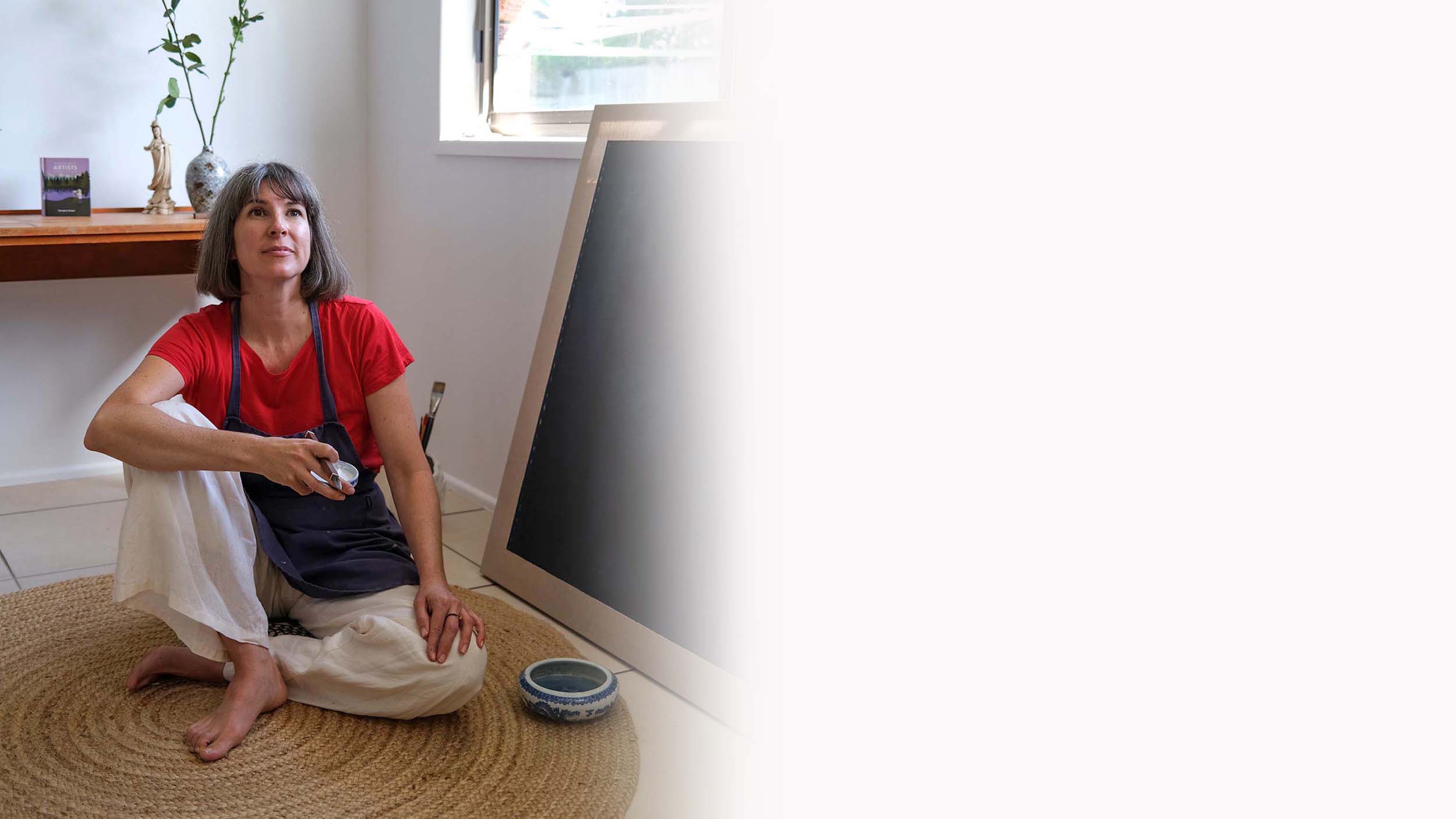 Georgina Hooper sitting in her sunny art studio, looking reflectively into the distance.