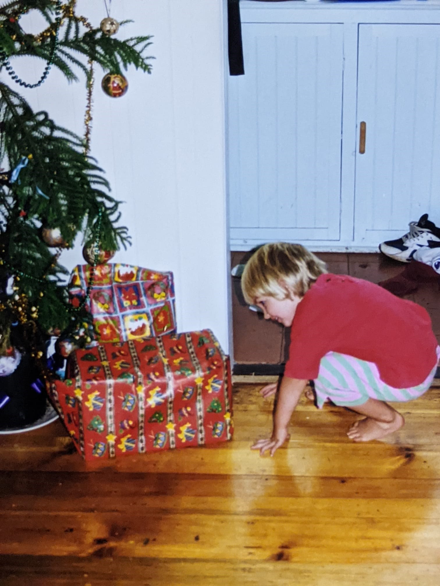 Jessie as a child looking at presents underneath the Christmas tree.