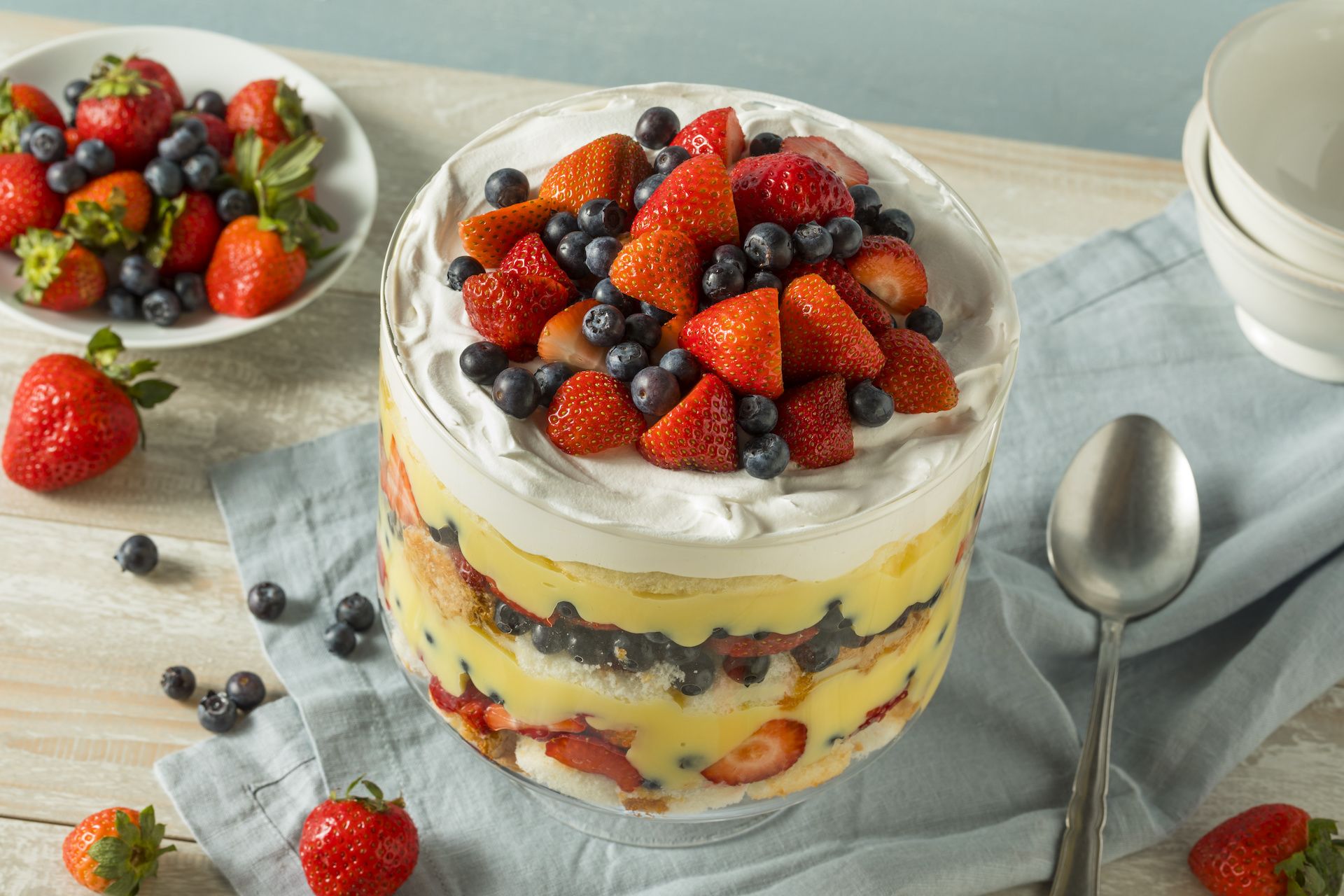 Strawberry trifle in a large glass bowl on a white table.