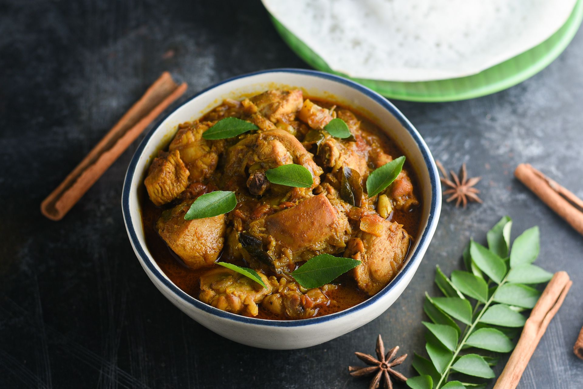 Kerala duck curry in a bowl with appam on the side.