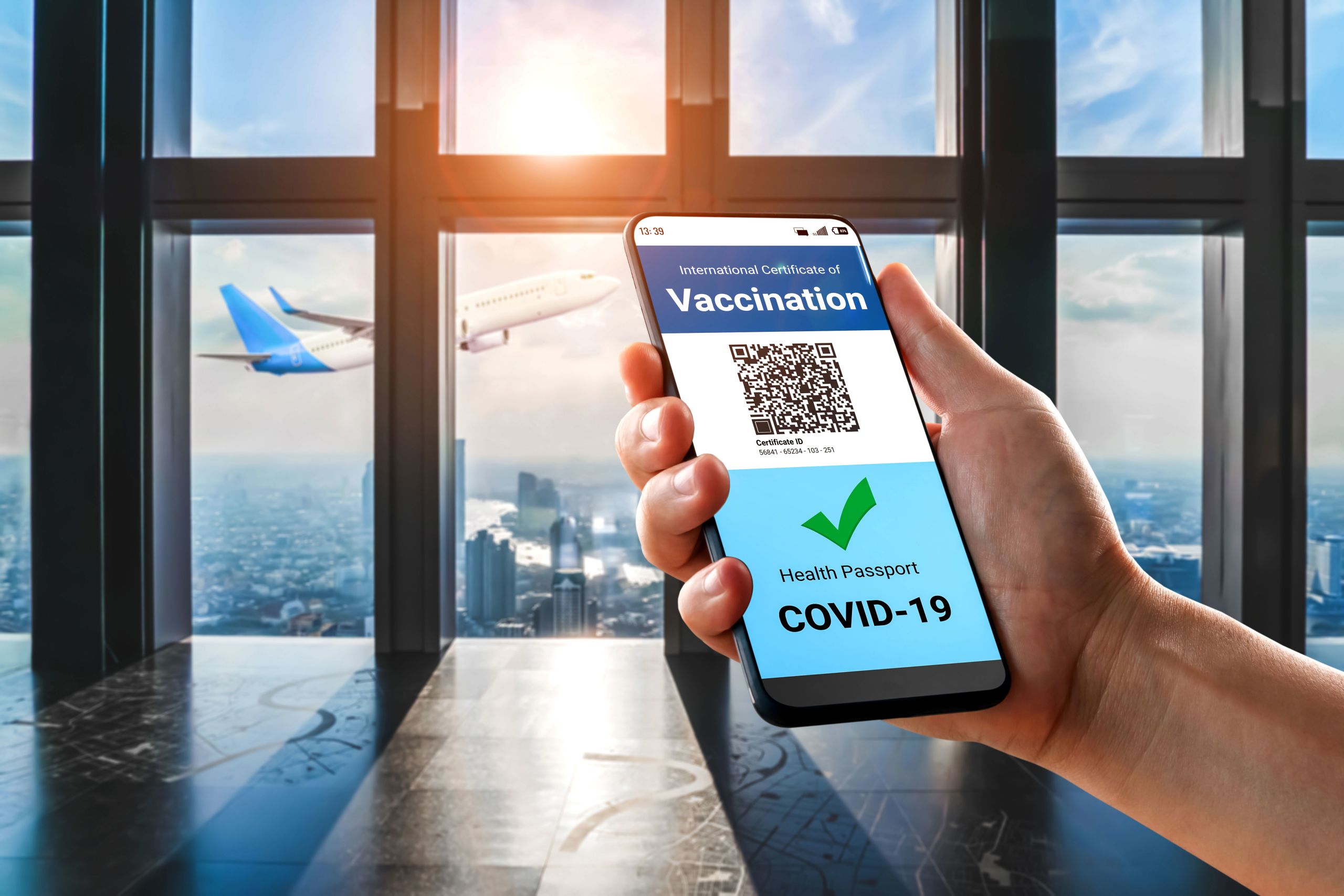 An image of a person holding a smartphone which shows a certificate of vaccination on the screen.