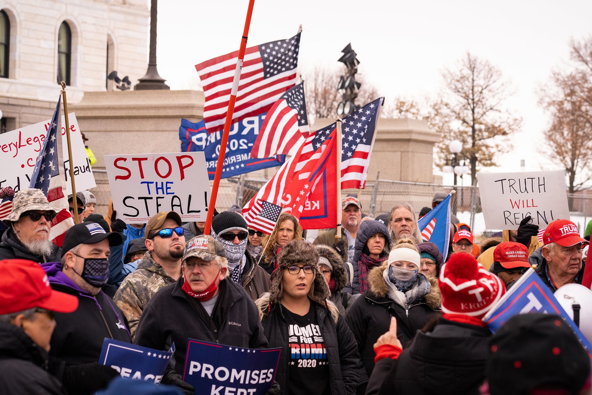 Protestors of all age and gender are at the Capitol in Washington D.C. in the United States. Many are holding American Flags or signs saying 'Stop the Steal' and 'Truth will Reign' and 'Trump 2020'.