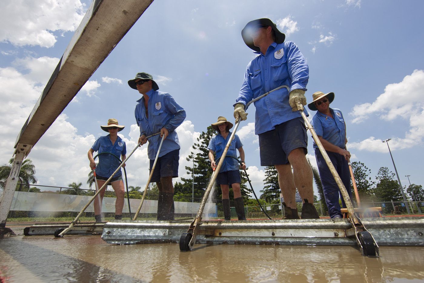 An image of UQ grounds staff cleaning the mud off the UQ Athletics Centre running track.