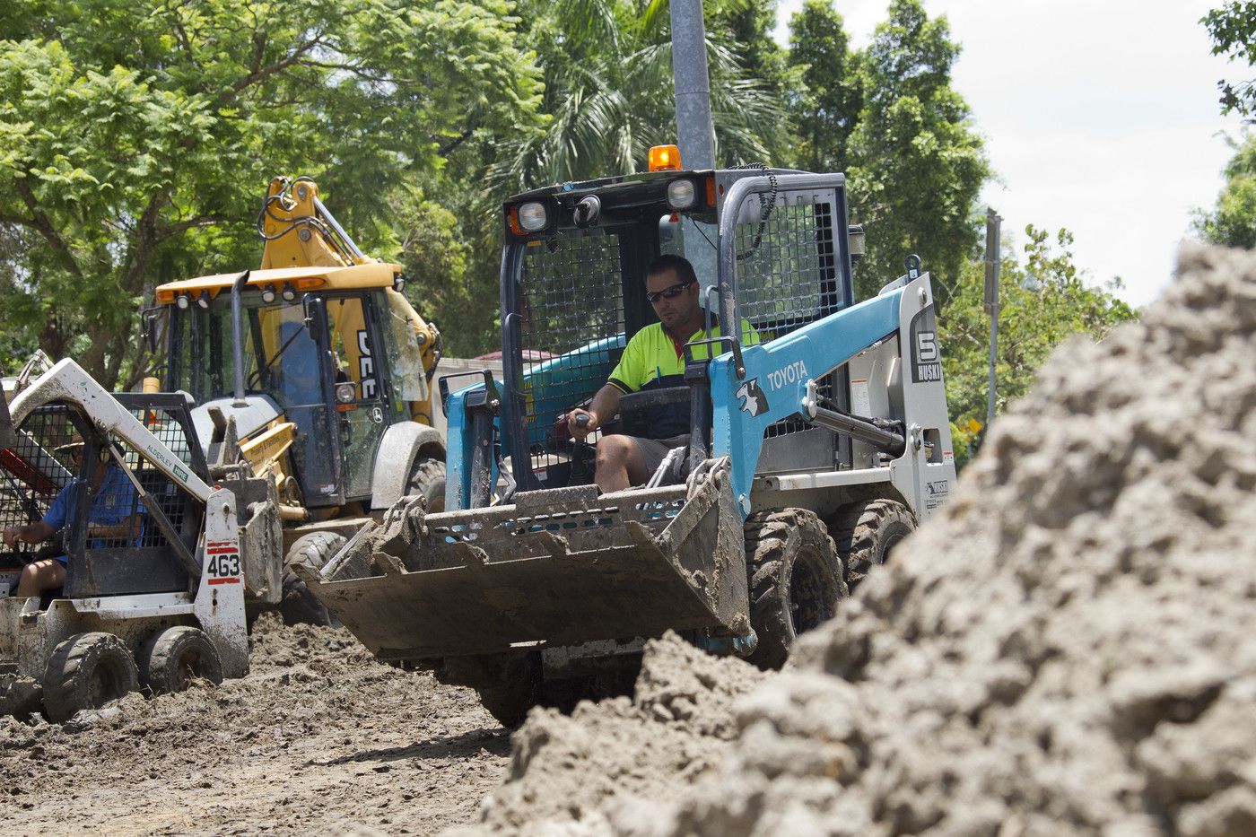An image of a worker in a bobcat clearing away the mountains of mud left on campus after the floods.