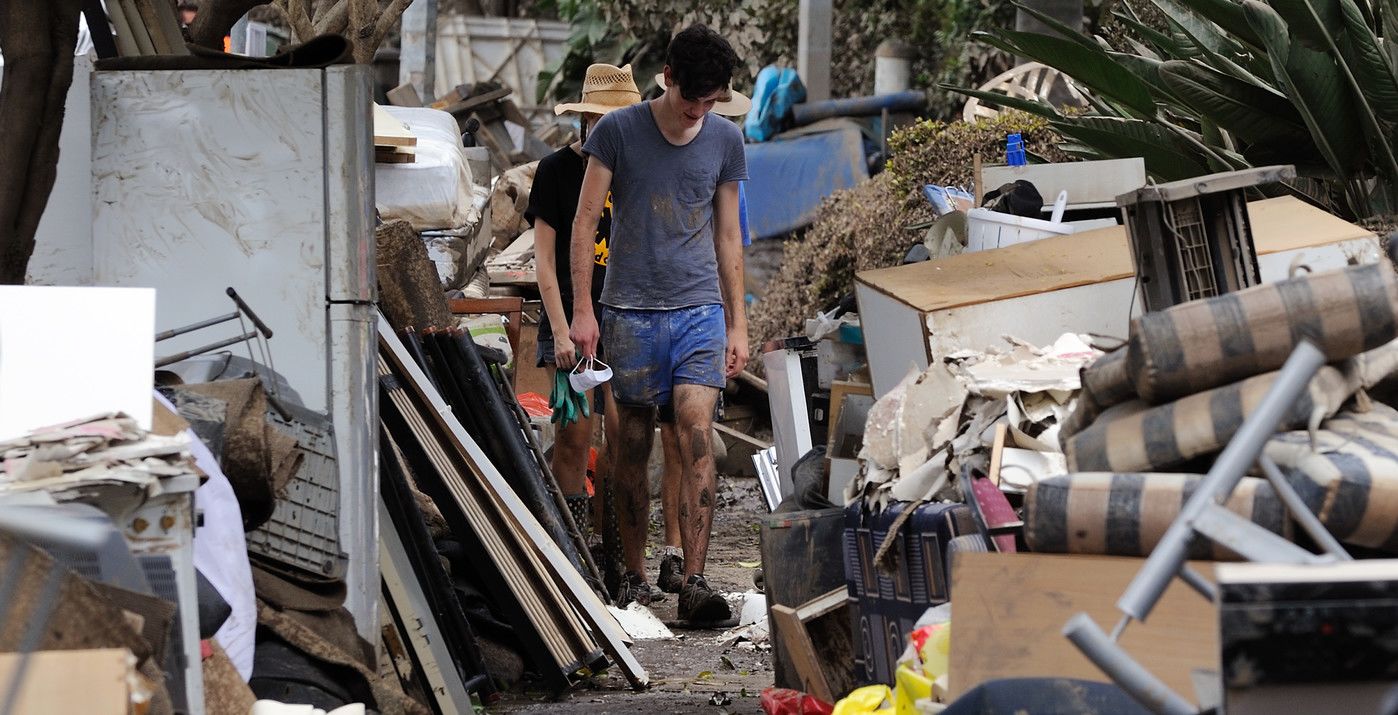 An image of clean-up volunteers walking through piles of debris.