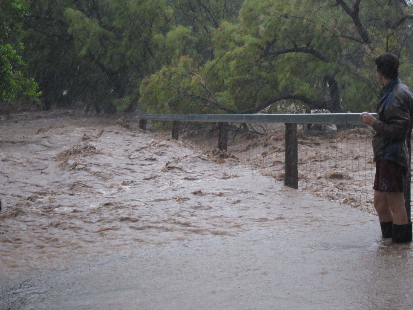 An image of Flood water gushing across a pedestrian bridge.