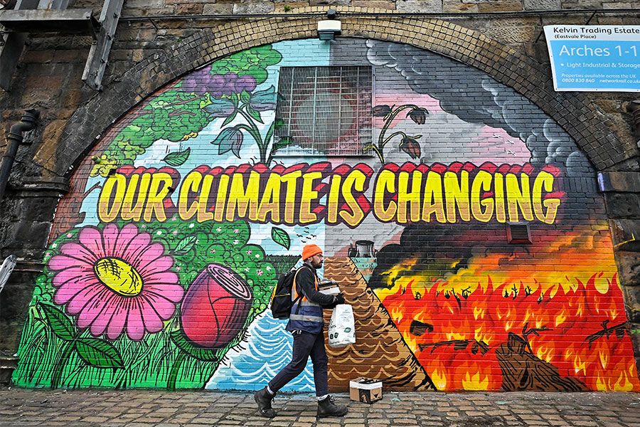 An image of an artist walking by his mural near the Scottish Events Centre, which will be hosting the UN Climate Change Conference.
