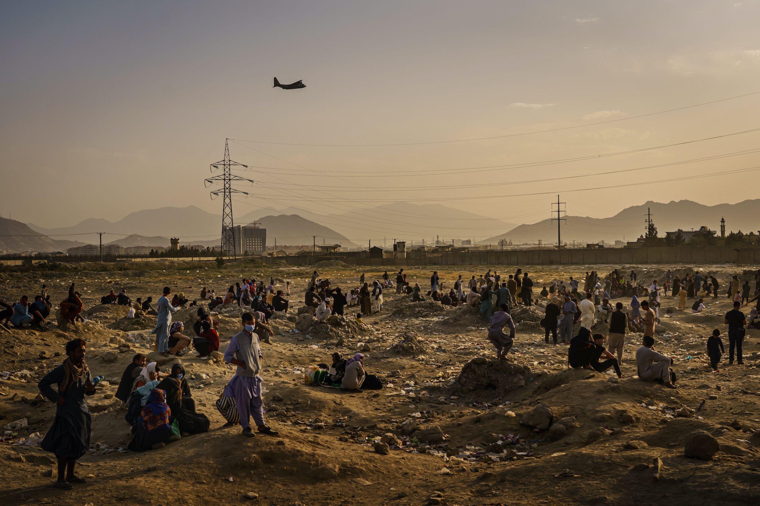 A military transport plane launches off while Afghans who cannot get into the airport to evacuate, watch and wonder while stranded outside, in Kabul, Afghanistan on 23 August, 2021.